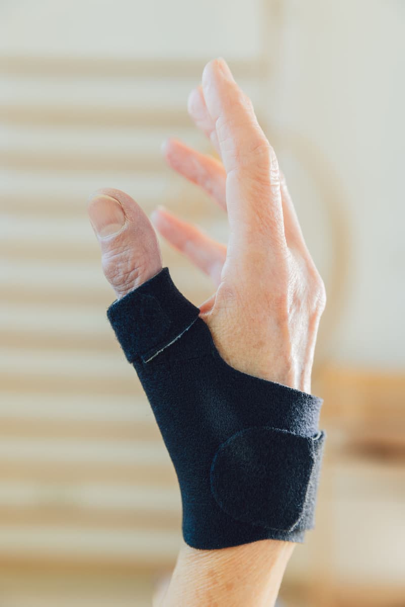 Hand mit schwarzer Schiene des Daumens
